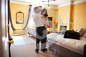 Middle aged couple embrace, smiling in their hotel room