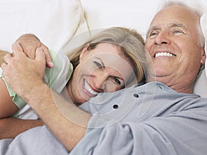 Middle Aged Couple Embracing In Bed