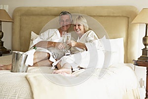 Middle Aged Couple Enjoying Champagne In Bedroom