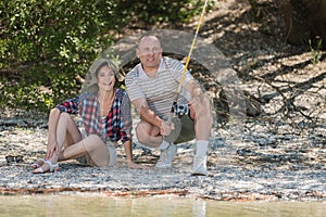 Middle-aged couple fishing from riverbank