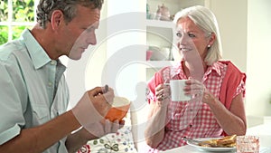 Middle Aged Couple Having Breakfast Together In Kitchen