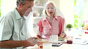 Middle Aged Couple Having Breakfast Together In Kitchen