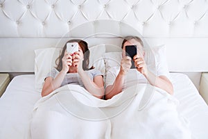 Middle aged couple hold mobile phones in bedroom, modern people concept photo