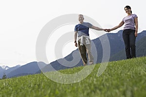 Middle Aged Couple Holding Hands On Meadow