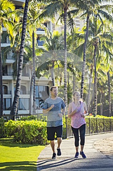 Middle aged couple jogging together at a tropical beach resort