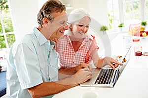 Middle Aged Couple Looking At Laptop Over Breakfast