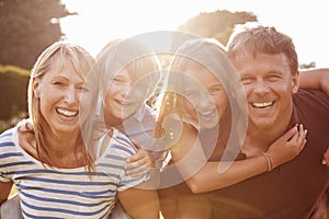 Middle aged couple piggybacking their kids smile to camera