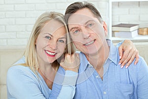 Middle aged couple relaxing on the couch smiling at camera at home in the living room