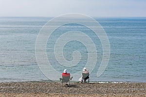 A middle-aged couple sit on the sea shore watching the horizon