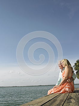 Middle Aged Couple Sitting On Pier