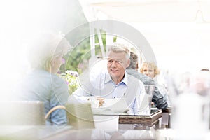 Middle-aged couple sitting at sidewalk cafe on sunny day