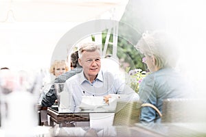 Middle-aged couple sitting at sidewalk cafe on sunny day