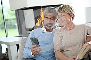 Middle-aged couple sitting on sofa by fireplace