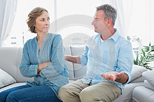 Middle aged couple sitting on the sofa having a dispute