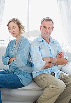 Middle aged couple sitting on the sofa not speaking after a dispute