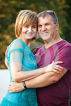 Middle-aged couple smiling and hugging on a city street, selective focus