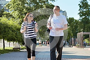 Middle-aged couple in sportswear walking and talking in the park