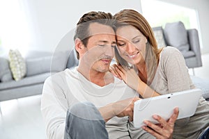 Middle-aged couple with tablet websurfing at home