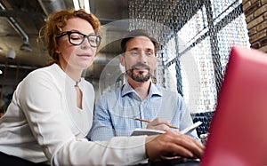 Middle-aged couple working on laptop and taking notes