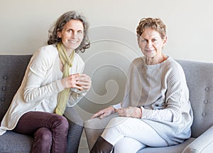 Middle aged daughter in green scarf smiling next to older mother