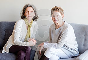 Middle aged daughter seated next to older mother