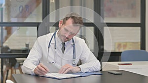Middle Aged Doctor Writing a Document, Medical Report