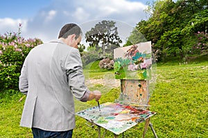 Middle-aged fashionable male painter mixing colors