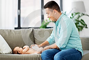 Middle aged father changing baby`s diaper at home