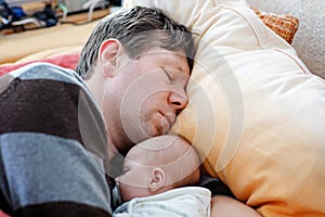 Middle aged father sleeping near his newborn baby daughter