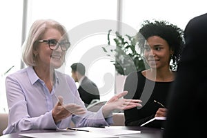 Middle aged female boss in eyeglasses conducting meeting with partners.