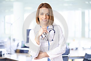 Middle aged female doctor portrait while standing in the doctor`s office