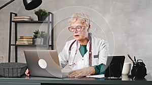 A middle-aged female doctor talks to a video conference patient. Telemedicine, online patient consultation