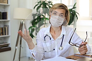 Middle aged female doctor therapist in medical mask on consultation