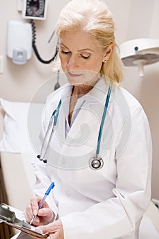 Middle Aged Female Doctor Writing On A Clipboard