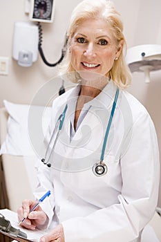 Middle Aged Female Doctor Writing On A Clipboard
