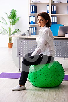 The middle-aged female employee doing exercises in the office