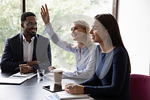 Middle-aged female employee raise hand at office meeting