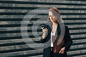 Middle-aged female with ginger hair typing on smartphone