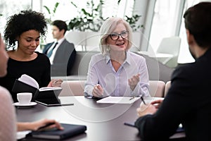 Middle aged female mentor conducting training meeting with young professionals