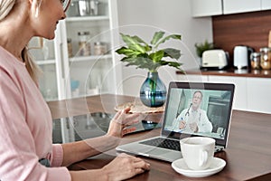 Middle aged female patient getting online telemedicine consultation at home.