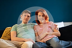 Middle aged well-rested man and woman mature loving married couple relaxed sitting on couch at home.