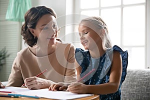 Middle-aged granny help little granddaughter with homework photo