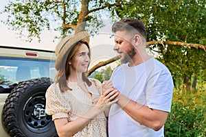 Middle-aged happy couple outdoors on a walk, man gives flowers to woman