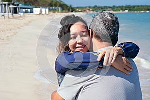 Middle-aged Hispanic couple hugging on a beach