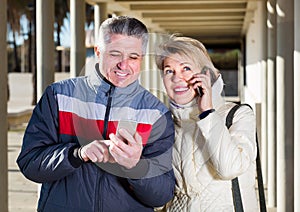 middle-aged husband and wife go nearby with each other and speak by mobile phone