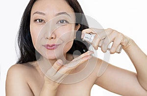 Middle-aged Japanese woman applying foundation on her cheeks