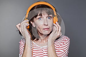Middle aged lady pulling headphone away from ear