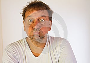 Middle-aged Latino man with the cheeks of his face inflated with air. Comic image with a mouth full of air and bulging eyes
