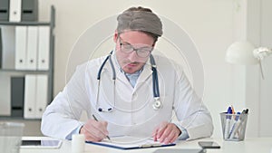 Middle Aged Male Doctor Writing on Paper