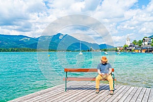 Middle aged male sitting on a bench by the Lake Wolfgangsee, Austria
